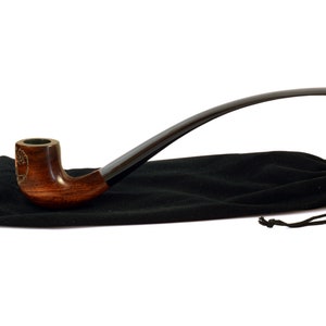 May include: A brown wooden smoking pipe with a black stem and a tree design on the bowl. The pipe is resting on a black velvet pouch.