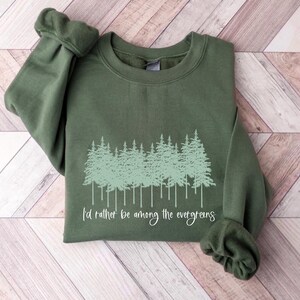 May include: A green sweatshirt with a forest scene and the text "I'd rather be among the evergreens".