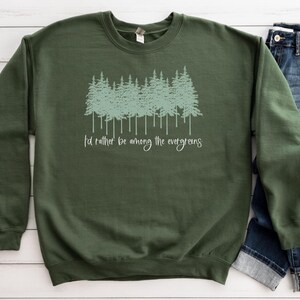 May include: A dark green sweatshirt with a light green graphic of a row of evergreen trees and the text "I'd rather be among the evergreens".
