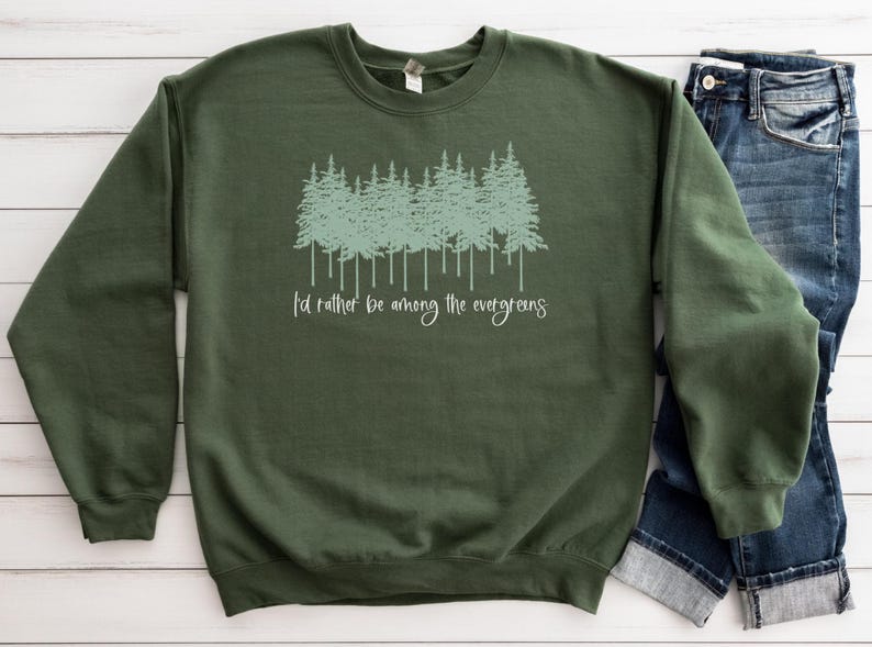 May include: A dark green sweatshirt with a light green graphic of a row of evergreen trees and the text "I'd rather be among the evergreens".