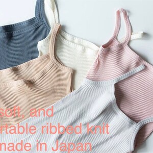 May include: Five ribbed knit tank tops in different colors: light blue, beige, white, pink, and gray.  "Nice, soft, and comfortable ribbed knit. Handmade in Japan." is written below the tops.