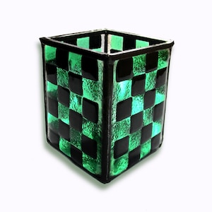 May include: A square glass vase with a checkerboard pattern in black and green.