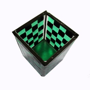 May include: A square green and black checkerboard patterned glass container with a black rim.