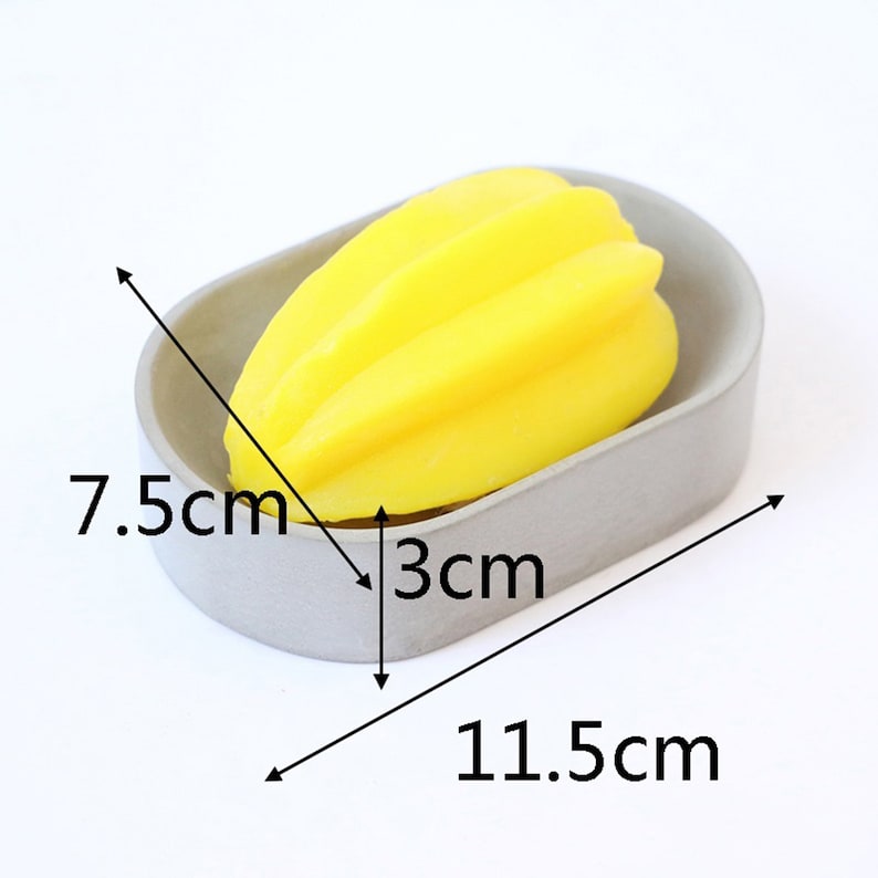 May include: A gray oval-shaped soap dish with a yellow starfruit-shaped soap inside. The dish measures 7.5 inches by 3 inches by 11.5 inches.