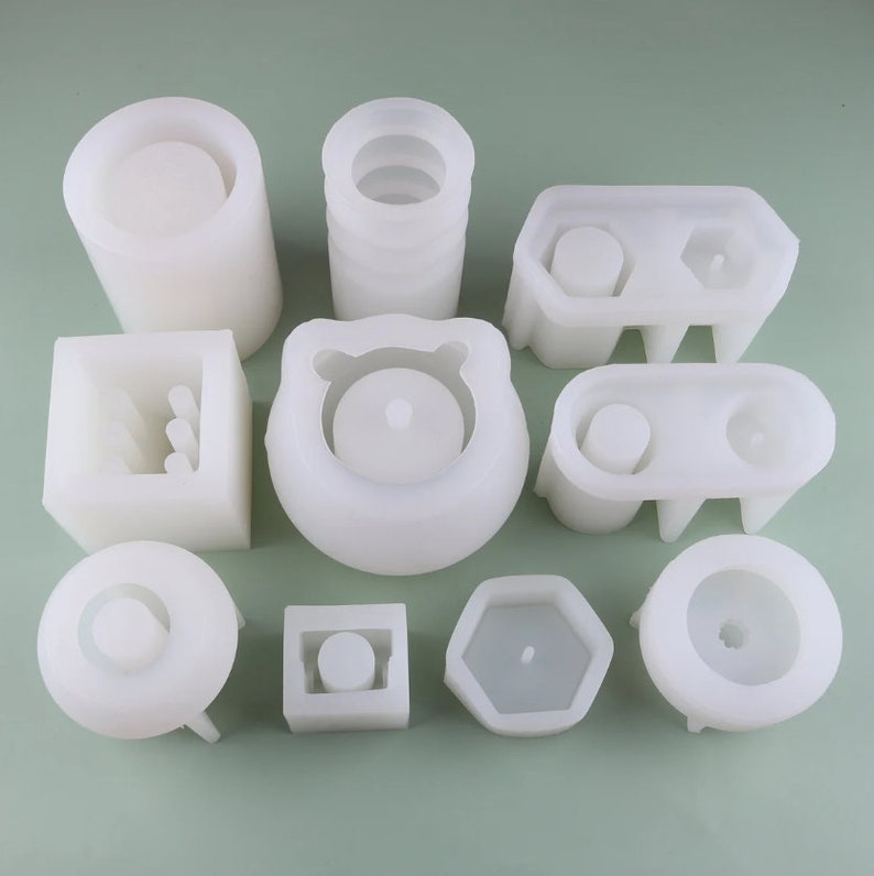 May include: A set of 10 white silicone molds for making concrete planters. The molds are in various shapes, including round, square, hexagonal, and rectangular.