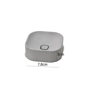 以下が含まれることがあります： 3cmの深さと7.8cmの幅の正方形のコンクリートプランター。プランターはわずかに丸みを帯びたトップと中央に小さな穴があります。