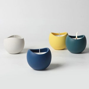 May include: Four round candles in different colors: white, yellow, blue, and teal. The candles are in a minimalist style and have a simple, modern design.