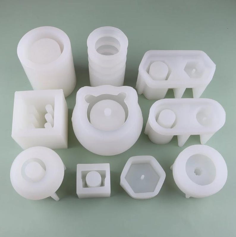 May include: Set of 10 white silicone molds for making concrete planters. The molds are in various shapes, including round, square, rectangular, and hexagonal.