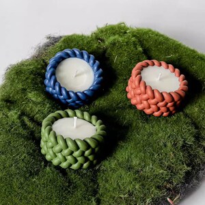 May include: Three tealight candles in woven candle holders. The holders are in blue, green, and orange.
