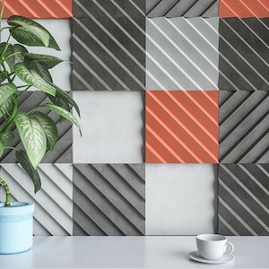 Peut inclure: Une surface blanche avec une plante dans un pot bleu et une tasse à café blanche sur une soucoupe blanche. L'arrière-plan est un mur avec un motif de carrés gris, blancs et orange.