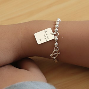 May include: Silver charm bracelet with a silver charm that says "Good luck with you".