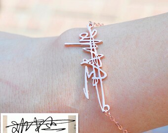 May include: A rose gold bracelet featuring a delicate chain and a personalised signature design. The signature is a stylised script.