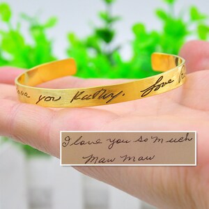 May include: Gold cuff bracelet with the inscription "I love you always" and a handwritten note that says "I love you so much Maw Maw".
