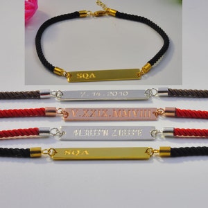 May include: Four personalized bracelets with different colored cords and engraved metal plates. The plates have the text "SQA", "7.IV.2010", "V.XXXIX.MMVIII", and "41.3837&deg;N 2.1833&deg;E".