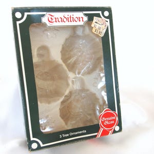 May include: A box of three glass Christmas tree ornaments. The box is green with a white border and the words "Tradition" in gold lettering. The ornaments are clear glass with a snowflake design. The box also says "Genuine Glass" and "3 Tree Ornaments".
