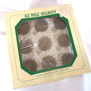 May include: A box of Old World ornaments, hand blown and hand painted. The box has a green border and the ornaments are visible through a clear plastic window.