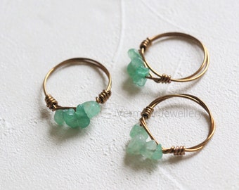 Puede incluir: Tres anillos de oro con detalles de piedras preciosas verdes. Los anillos están hechos de alambre fino y tienen un diseño simple.
