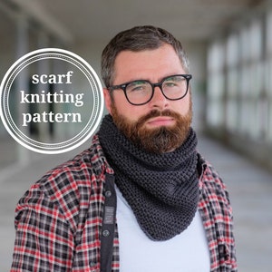 May include: A man wearing a grey knitted scarf with a plaid shirt and a white t-shirt. The scarf is a simple knit pattern.