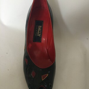 May include: Black peep-toe heels with geometric red and yellow accents. The shoes are made by Bally and say "Made in Italy" on the inside.