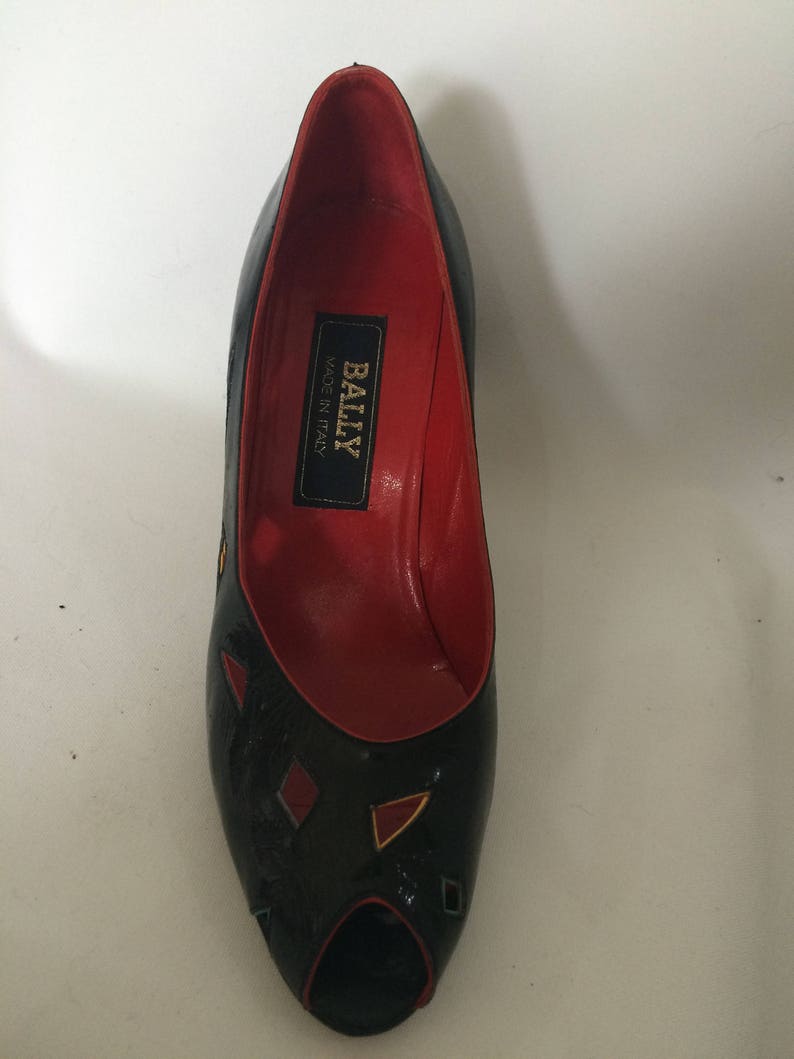 May include: Black peep-toe heels with geometric red and yellow accents. The shoes are made by Bally and say "Made in Italy" on the inside.