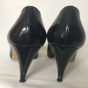 May include: A pair of black patent leather high heel pumps with stiletto heels.