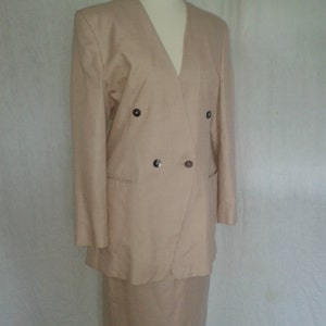 May include: A beige double-breasted blazer and matching skirt suit. The blazer has a V-neck and two buttons.
