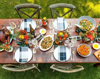 May include: A rustic wooden table set for a Thanksgiving dinner with a roasted turkey, side dishes, wine, and flowers.