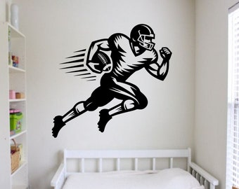 May include: Black and white silhouette of a football player running with the ball. The player is wearing a helmet and uniform. The image is a wall decal.