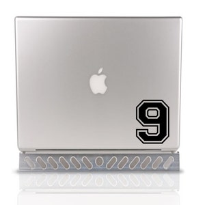 May include: A silver laptop computer with a black number 9 sticker on the back. The number is in a varsity style font.