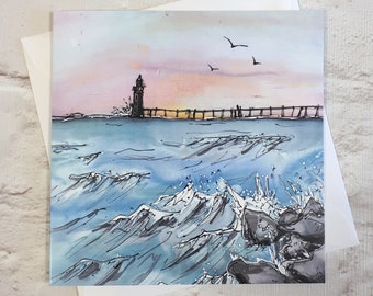 Op de afbeelding: Een aquarel schilderij van een vuurtoren op een pier met golven die tegen de rotsen in de voorgrond breken. De lucht is zacht roze en oranje, met een paar vogels die erboven vliegen.