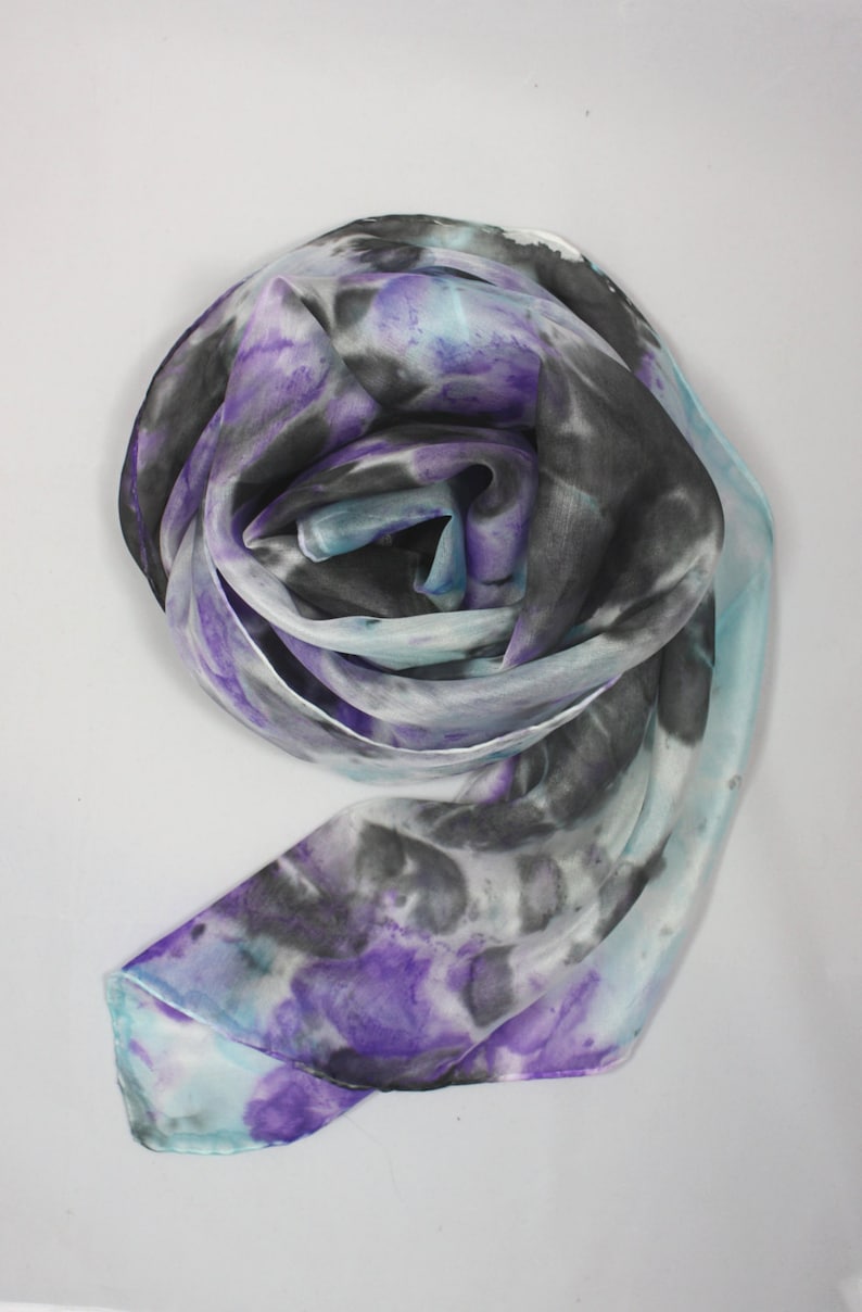 May include: A white silk scarf with a tie-dye pattern in shades of purple, blue, and black.