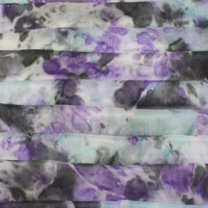 May include: A white silk scarf with a tie-dye pattern in shades of purple, blue, and black.