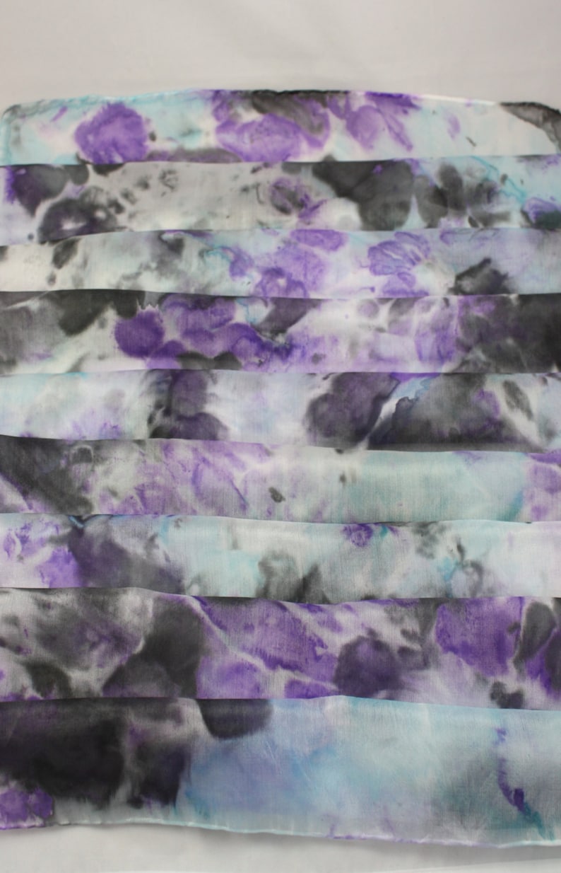 May include: A white silk scarf with a tie-dye pattern in shades of purple, blue, and black.