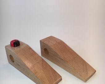 May include: Two wooden ramps with a small red ladybug toy on top of one of the ramps. The ramps are made of light brown wood and have a smooth surface.
