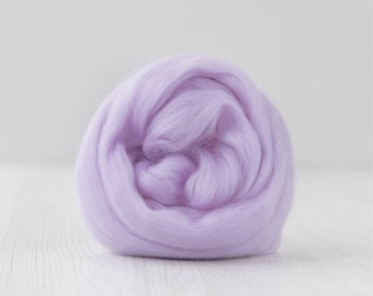 Puede incluir: Una bola de lana de color lila claro. La lana está enrollada firmemente, creando una apariencia densa y texturizada. El fondo es de un color claro y neutro, resaltando el vibrante tono lavanda de la lana.
