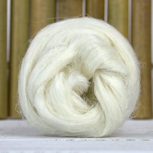 Puede incluir: Un primer plano de una bola de fibra de kapok blanca. La fibra es suave y esponjosa, y es perfecta para rellenar almohadas, cojines y otros artículos.