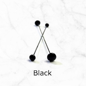 May include: Three black headed pins with thin metal shafts. The pins are crossed over each other. The text "Black" is written below the pins.
