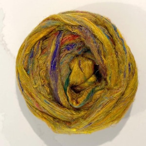 May include: A ball of golden yellow silk fiber with streaks of purple, blue, and green.