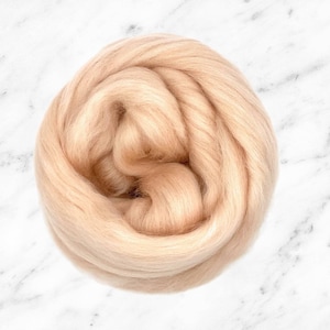 May include: A close-up of a light beige ball of wool fibre. The wool is soft and fluffy, and it is perfect for knitting or crocheting.