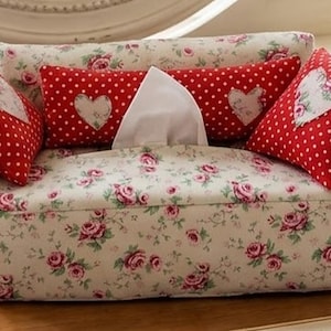 May include: A sofa-shaped tissue box cover featuring a cream fabric with a pink rose floral pattern. It includes two red and white polka dot side cushions with heart-shaped patches and a long red and white polka dot back cushion.