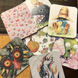 May include: Set of 10 colorful mouse pads featuring various cartoon characters and designs. The mouse pads are rectangular and have a smooth surface. Some of the designs include a green monster, a white wolf, a black and white monster, a pink and white character, and a black and white character with a red mask.
