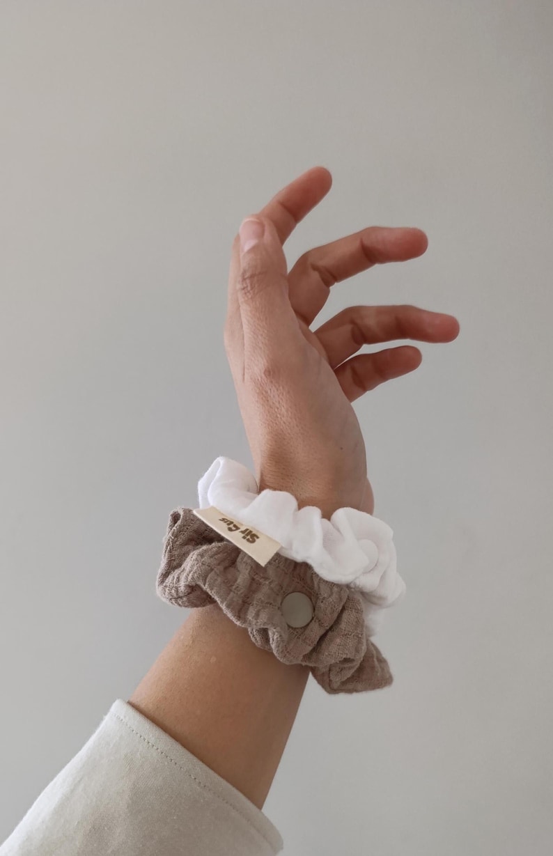 Puede incluir: Dos coleteros de tela, uno en blanco s&oacute;lido y otro en tela de color marr&oacute;n claro texturizada. El coletero marr&oacute;n presenta una peque&ntilde;a etiqueta de tela rectangular de color beige con el texto Sir Gus impreso en marr&oacute;n y un bot&oacute;n circular.