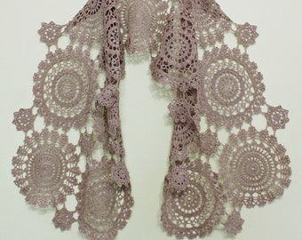 May include: A brown crocheted shawl made of delicate lace with a scalloped edge. The shawl is made up of multiple circular motifs.
