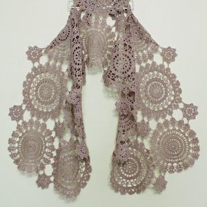 Beige lace crochet scarf hanging full length on a hanger against a light background, designed by Ukrainian designer Kate Kosenko Veselunka (ItWasYarn).
