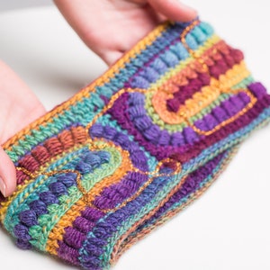 May include: A colorful crocheted headband with a rainbow pattern and gold accents.
