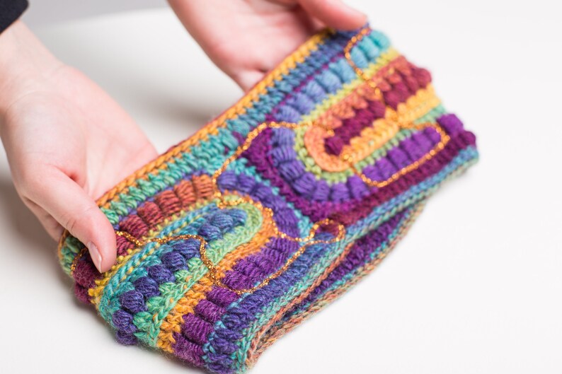 May include: A colorful crocheted headband with a rainbow pattern and gold accents.