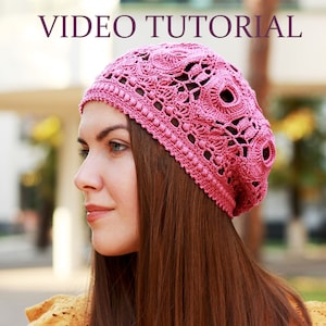 Puede incluir: Un gorro de punto rosa con un delicado patrón floral. El gorro lo lleva una mujer con el pelo largo y castaño.