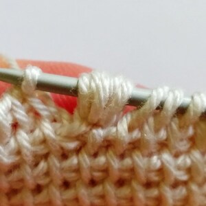 The process of crocheting Tunisian stitch using fine weight light-colored yarn.