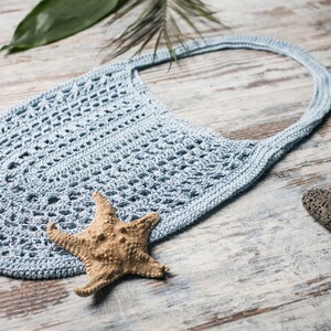 Boho-style crochet shoulder bag with airy lace texture, perfect for summer – shown on neutral background with sea elements