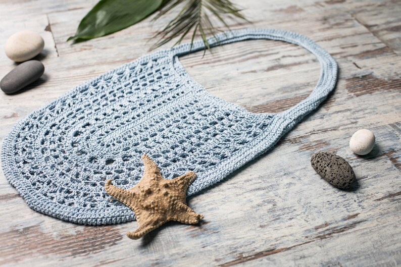 Boho-style crochet shoulder bag with airy lace texture, perfect for summer – shown on neutral background with sea elements